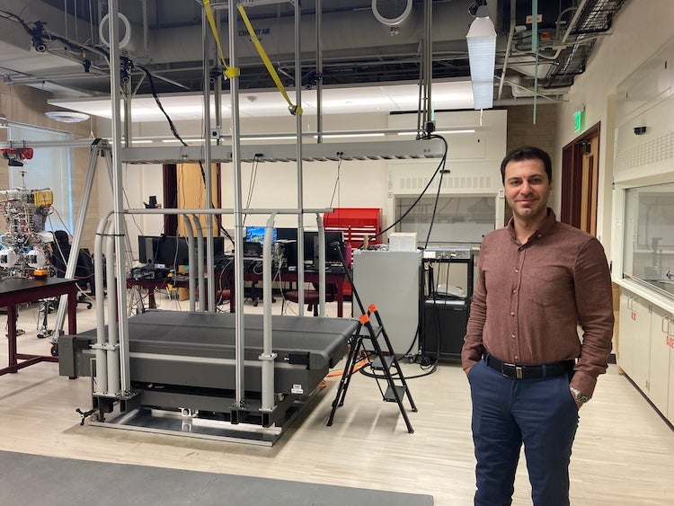 Professor Siavash Rezazadeh standing next to the raised treadmill
