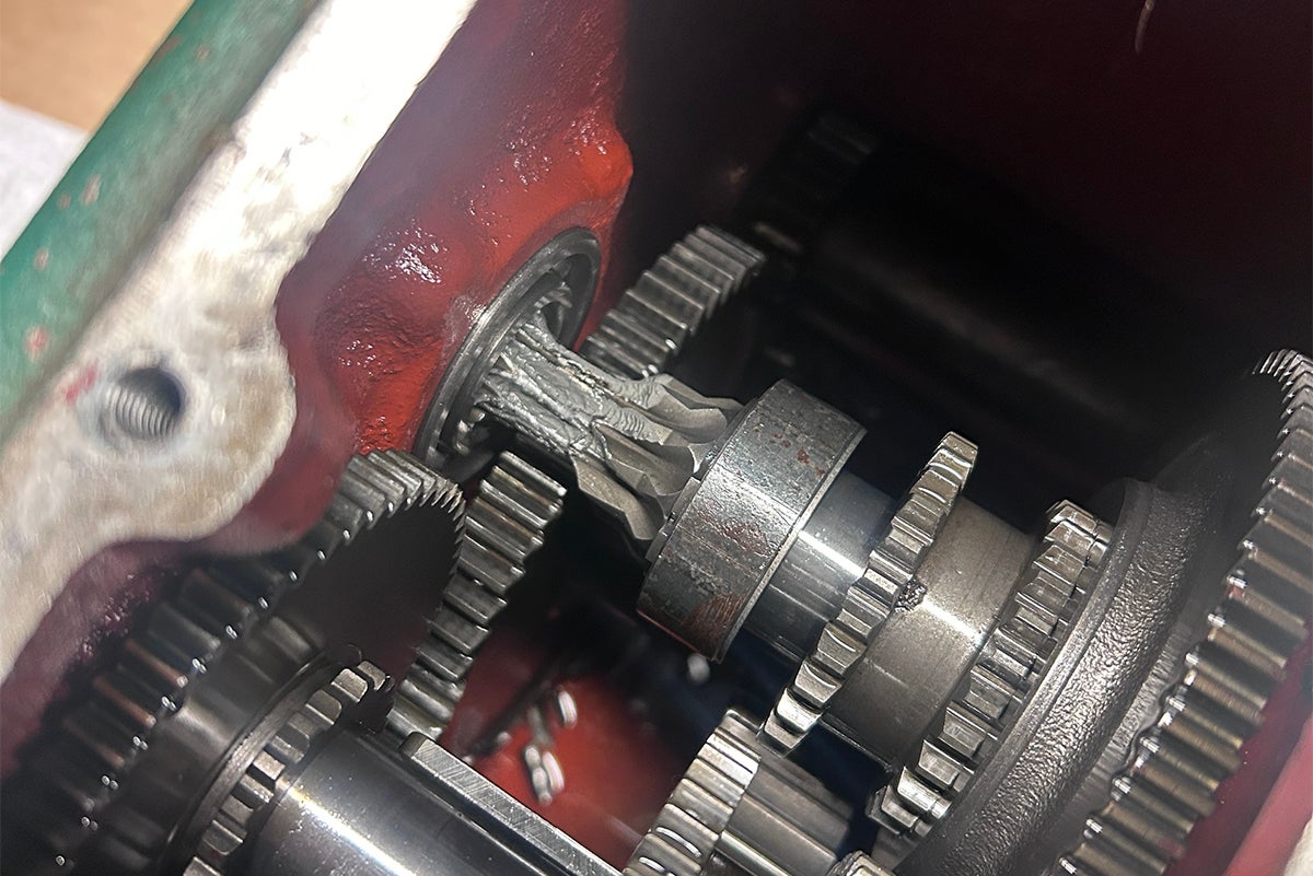 A green gearbox containing several broken gears