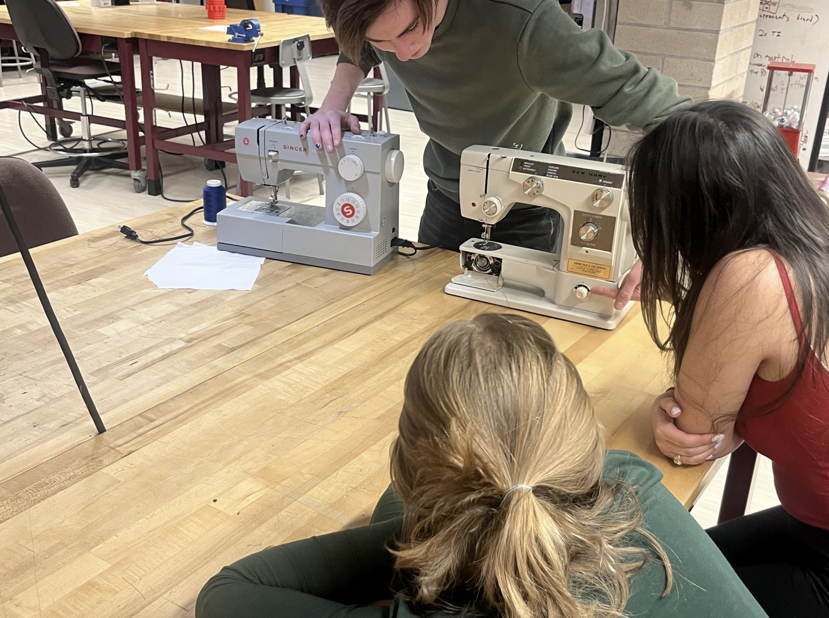 Students in the Innovation Lab gathering around the sewing machine