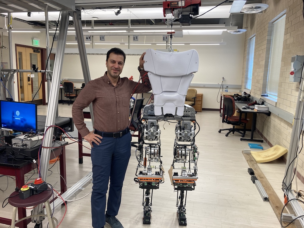 Professor Siavash Rezazadeh standing next to Mithra the Robot
