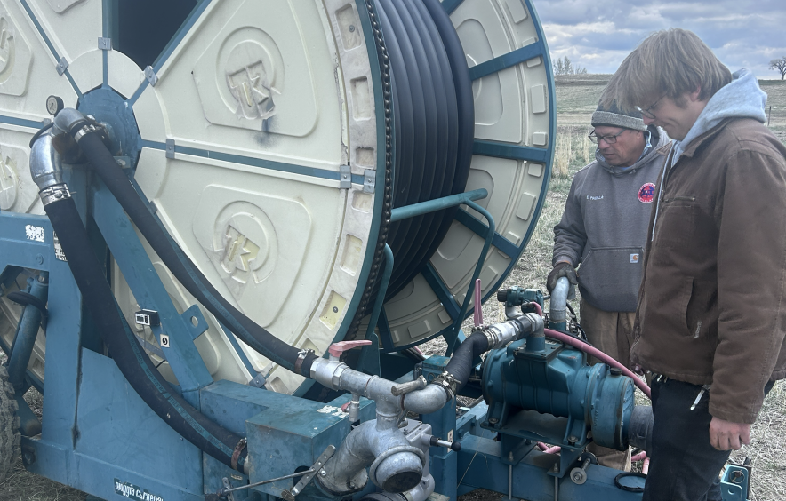 Uton Delloso and a farm employee installing the gearbox in an irrigation machine