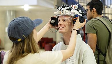 A student placing an EEG device on another student's head