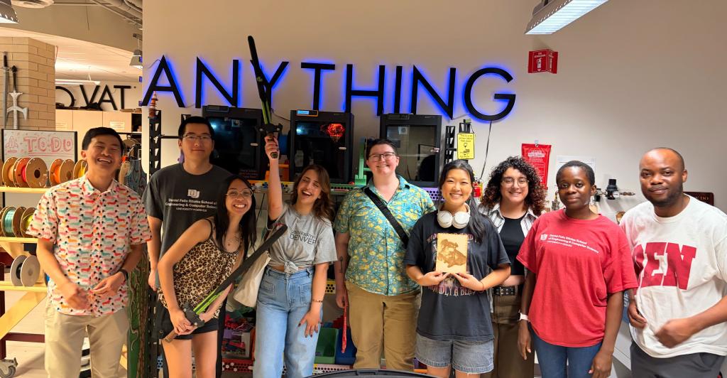 people smiling while standing in maker space holding assorted 3D printed items